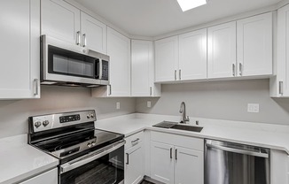 A kitchen with white cabinets and a black microwave.