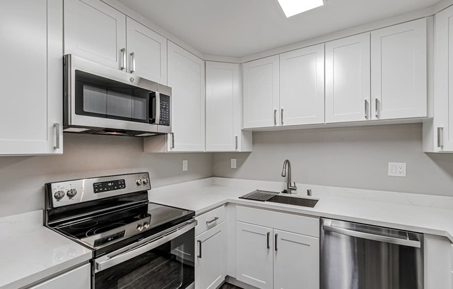 A kitchen with white cabinets and a black microwave.