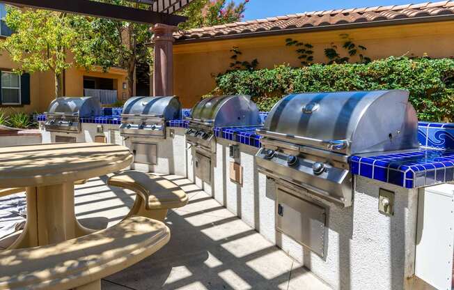 A row of outdoor grills are lined up on a patio.