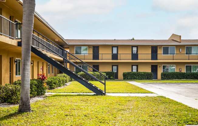 an exterior view of an apartment building with a lawn and a staircase