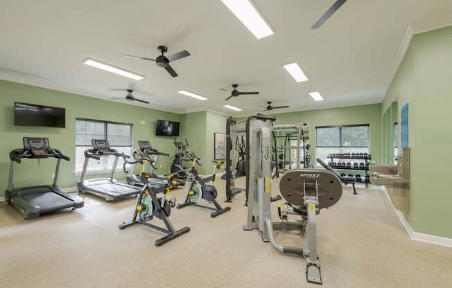 A spacious gym with a variety of exercise equipment including treadmills, stationary bikes, and weight machines.