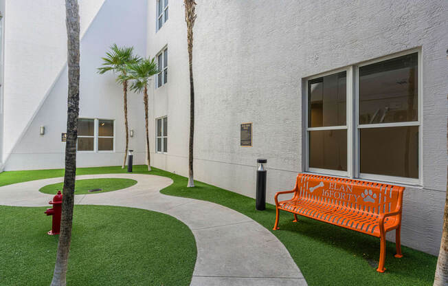 an orange bench in front of a white building with palm trees