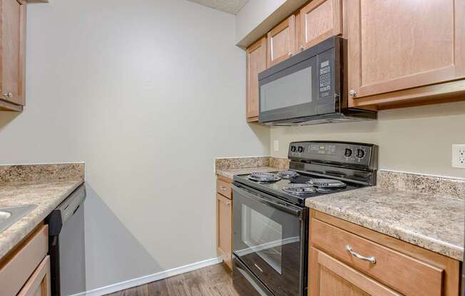 A kitchen with a black stove top oven and microwave above it. Omaha, NE Evergreen Terrace Apartments
