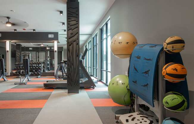 a fitness room with weights and other equipment in a building with windows