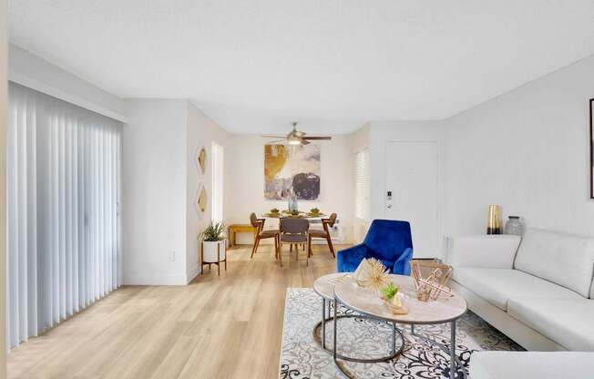 A living room with a white couch, a coffee table, and a dining table with chairs at Verandas Apartments, California, 91791