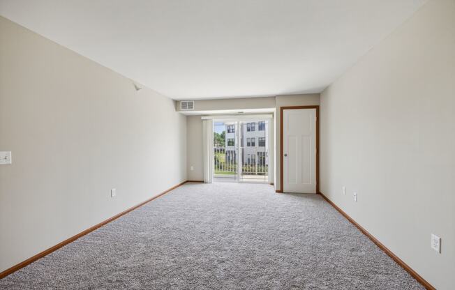 a living room with carpet and a door to a balcony