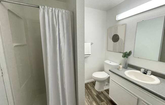 A bathroom with a white shower curtain and a white toilet.