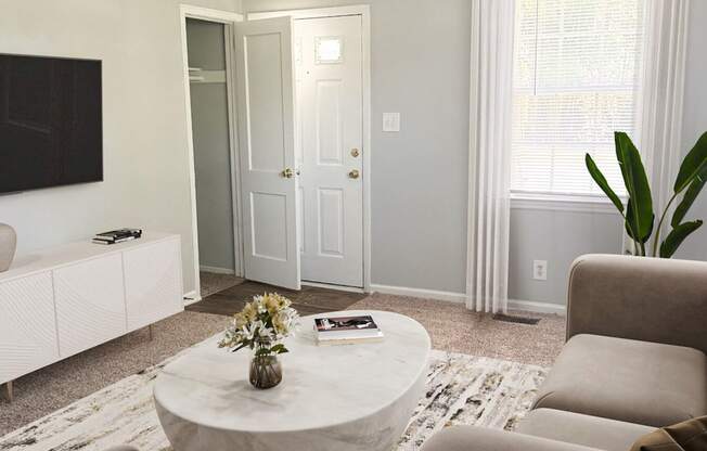 A living room with a white couch, a coffee table, and a flat screen TV.