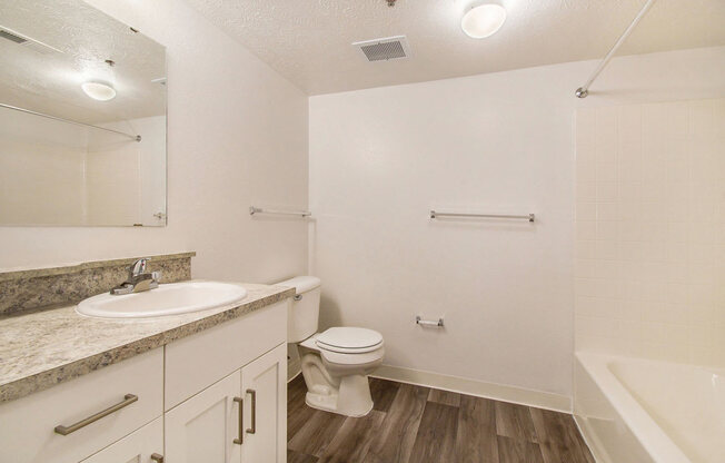 a renovated bathroom with hard surface floors and white cabinetry at Canal 2 Apartments, Lansing, Michigan