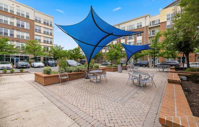 A blue shade structure is in the middle of a courtyard.