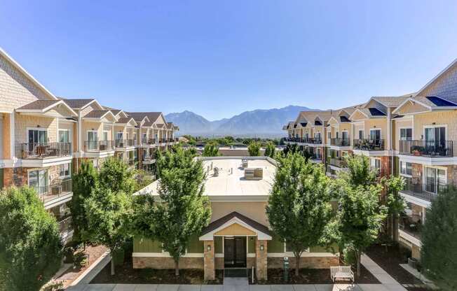 an aerial view of a building with trees in the foreground and mountains in the background at The Beckstead, South Jordan, 84095