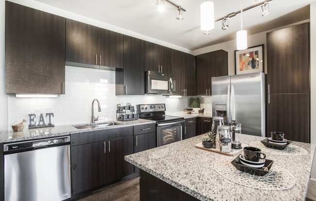 Kitchen with center island, dark wood cabinets, granite countertops and stainless steel appliances
