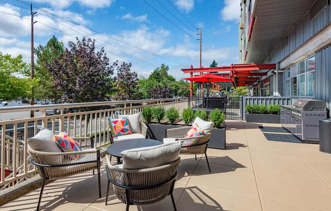 A patio with chairs and a table is surrounded by a metal fence.