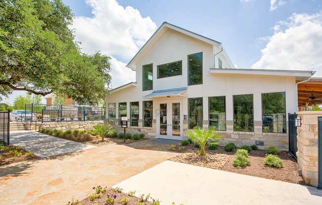 A white house with a black fence and a tree in front.