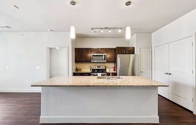 A kitchen with a granite countertop and stainless steel appliances.