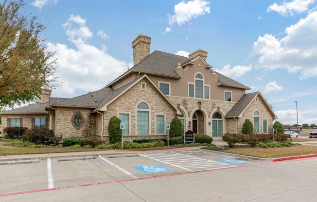 Leasing Clubhouse Exterior with cloudy skies, parking spaces, and green trees