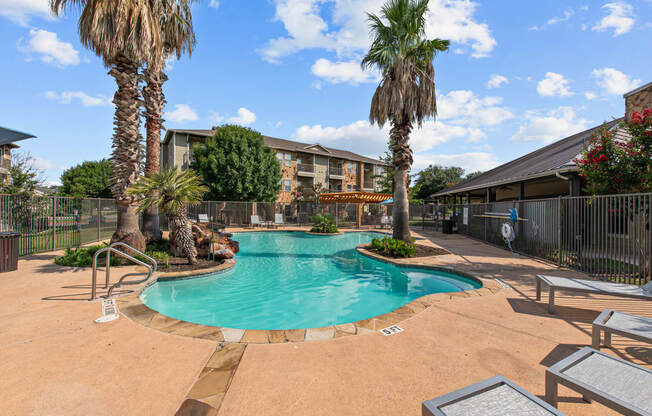 a swimming pool with palm trees and a building in the background