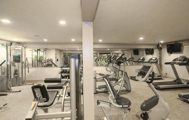 A well-lit gym with a variety of exercise equipment.