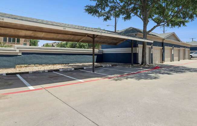 Reserved resident parking spots for compact cars with garages in the background at Encore at Buckingham Apartments in Richardson, TX
