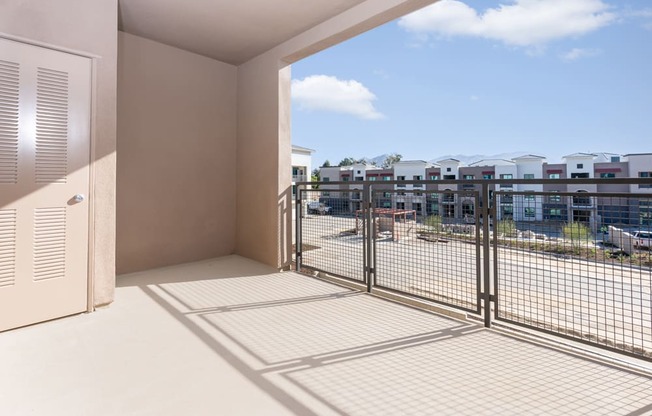 A balcony with a view of a parking lot and buildings.