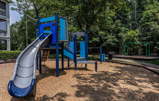 a blue playground with a slide in the middle of a park