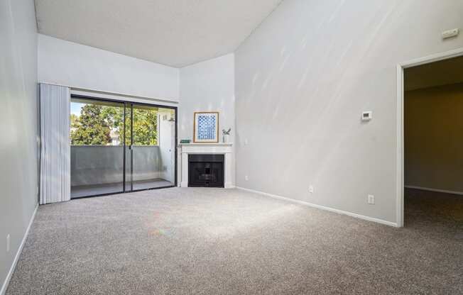 an empty living room with a fireplace and a sliding glass door