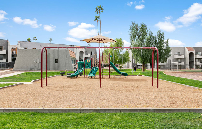 A playground with a green slide and a brown sandbox.