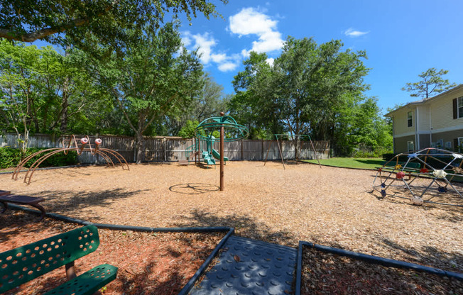 A playground with a green bench and a slide.
