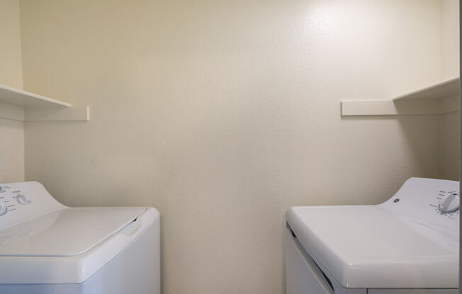 an empty laundry room with two washes and a dryer