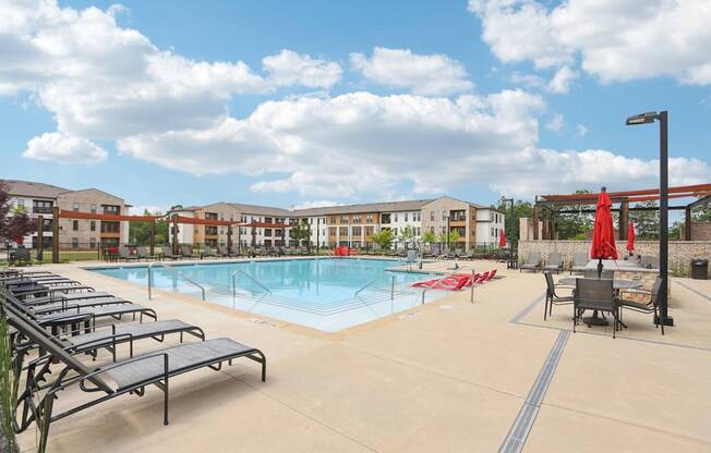 A large swimming pool with many lounge chairs and umbrellas.