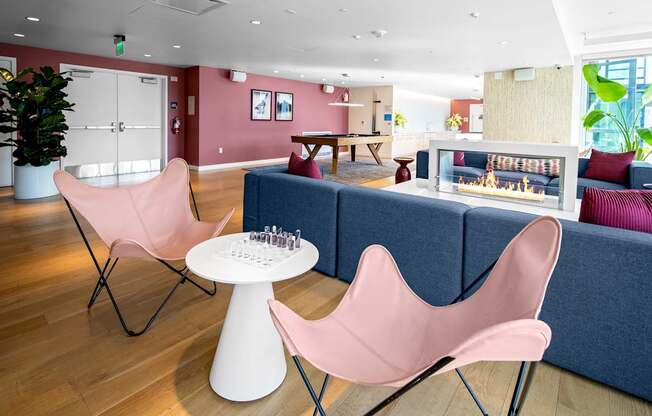 A living room with a pink chair and a white table.