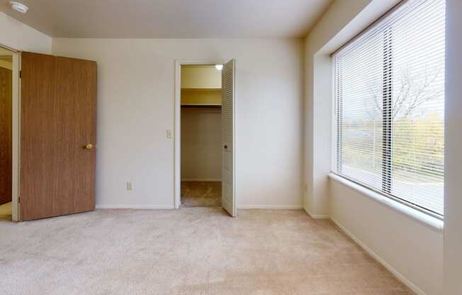 a bedroom with a large window and a door to a closet