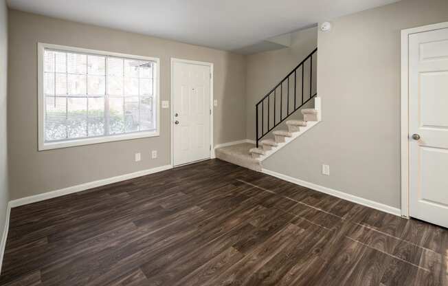 a bedroom with hardwood floors and a staircase