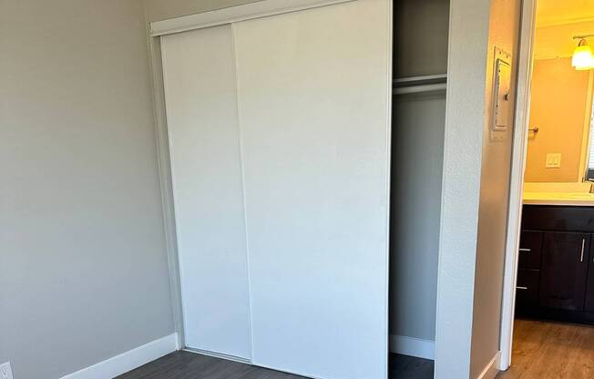 A white cabinet with a mirror above it in a room with wooden flooring.