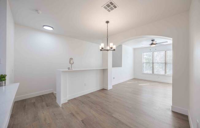 an empty living room and dining room with white walls and wood floors