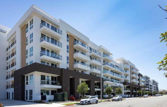 A row of modern apartment buildings with cars parked in front. at Elements Apartments*, California