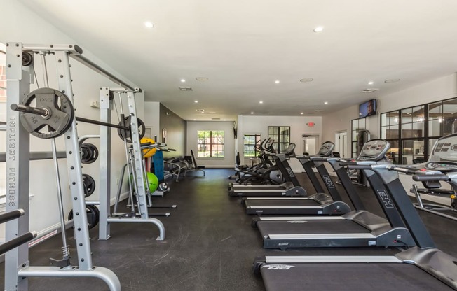 a gym with cardio equipment and weights on the floor