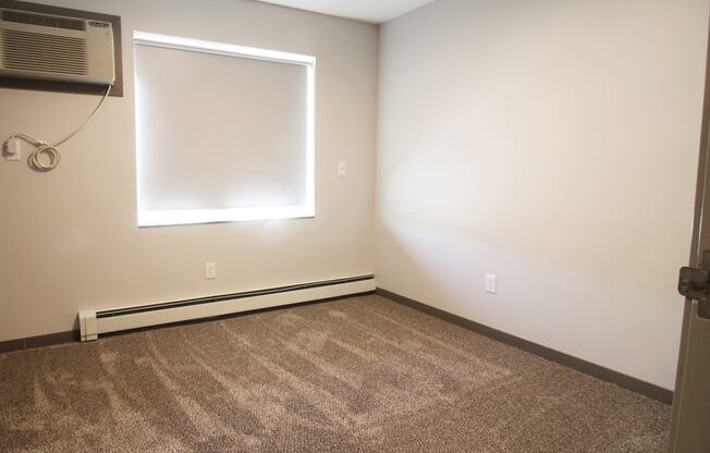 an empty room with a window and an air conditioner