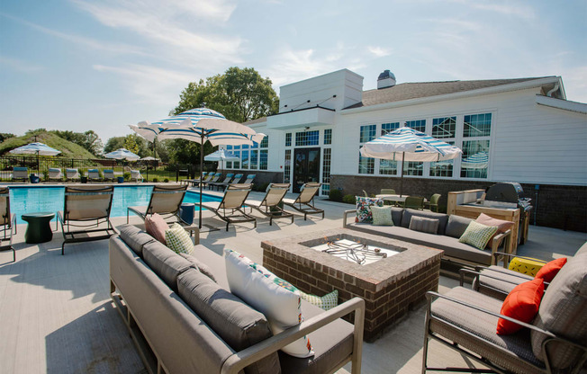 a patio with couches and umbrellas and a pool