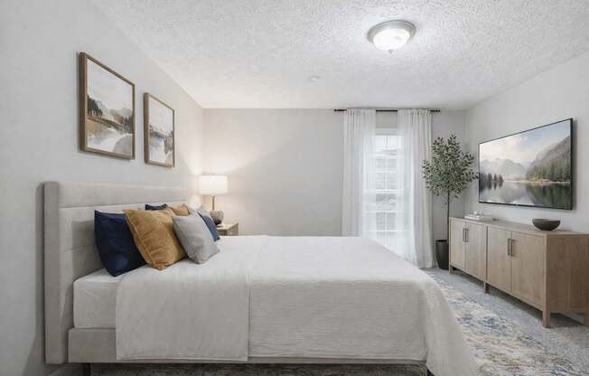 A bedroom with a large bed, a nightstand with a lamp, and a painting on the wall.