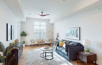 A bright living room here at Van Buren East with wood-style flooring and modern furnishings. A large window brings in natural light, while a cozy seating area creates a warm, inviting atmosphere.