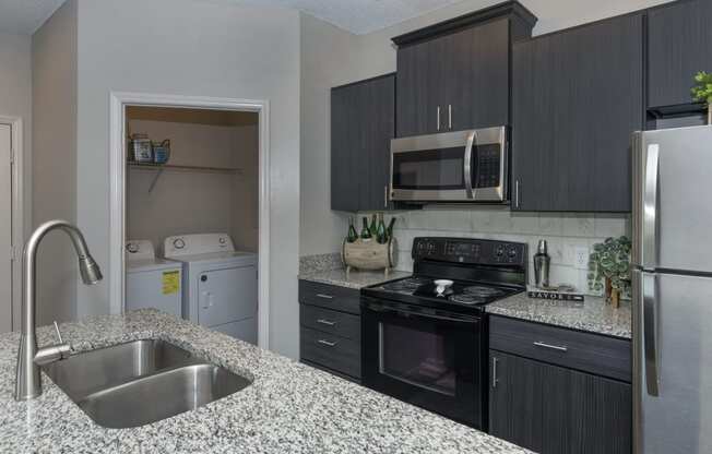 Seasons at Umstead apartments in Raleigh interior kitchen renovated appliances with view into washer dryer closet