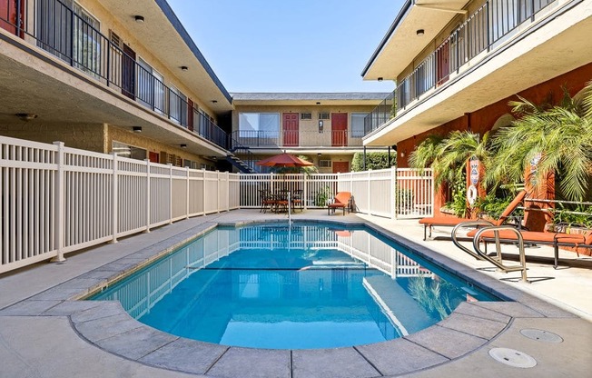 A small round pool in a courtyard surrounded by white railings.