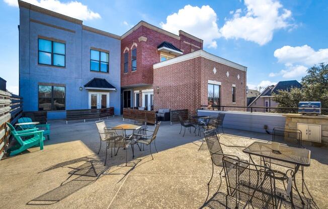 a patio with tables and chairs and a brick building in the background