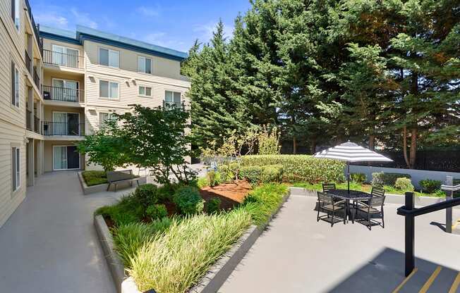 a courtyard with shaded area and a table and chairs with an umbrella at Guinevere Apartment Homes, Washington