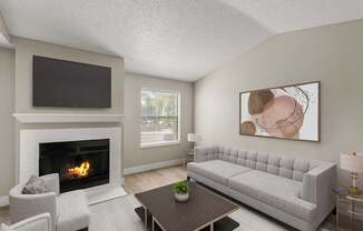 A living room with a fireplace, a grey sofa, a coffee table, and a painting on the wall.