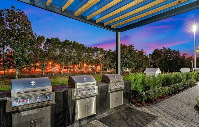 a group of stainless steel gas grills under a blue and yellow roof