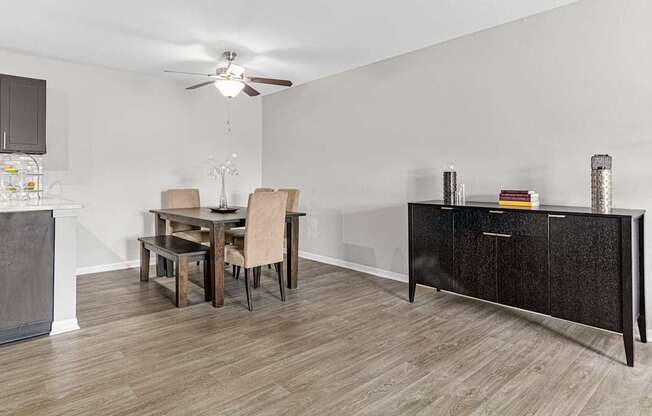 a dining room with a table and chairs and a kitchen with a cabinet