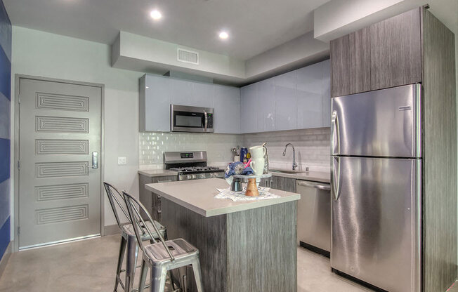 Kitchen With Island And Bar Seating And Stainless Steel Appliances At The Mansfield at The Mansfield at Miracle Mile, Los Angeles, CA , 90036