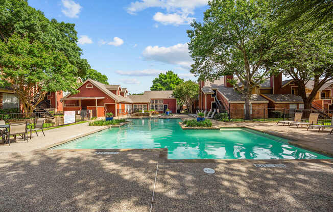 A large swimming pool surrounded by trees and a building in the background.
